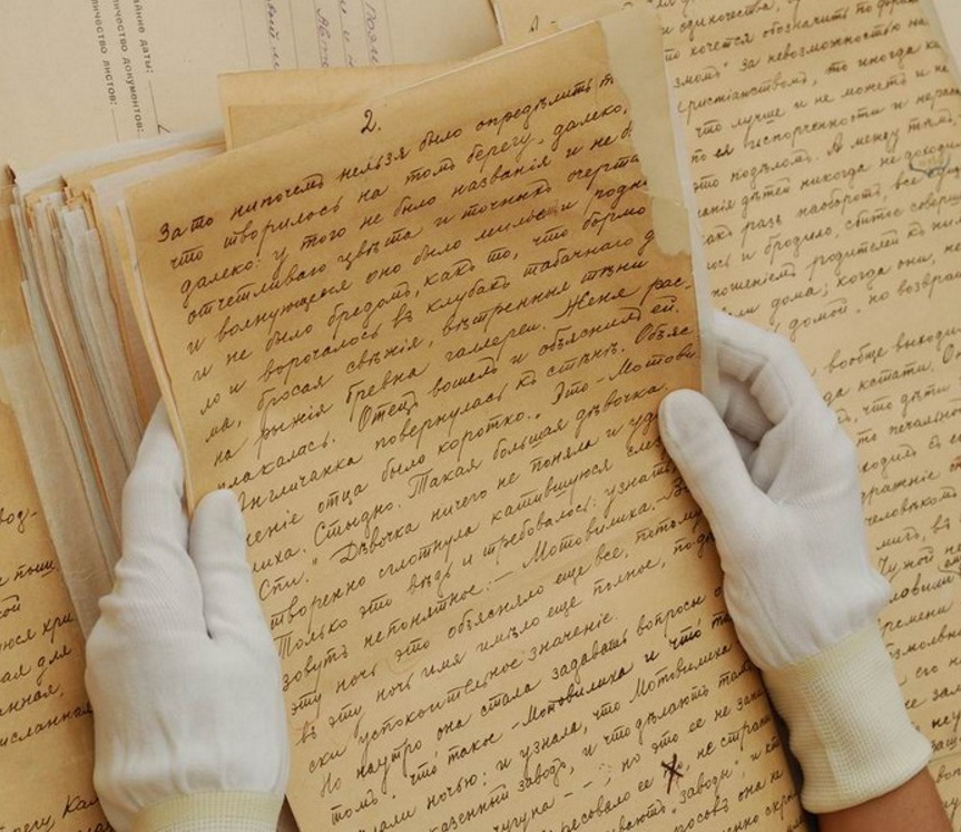 Изображения рук эксперта в специальных перчатках держащих рукописный текст